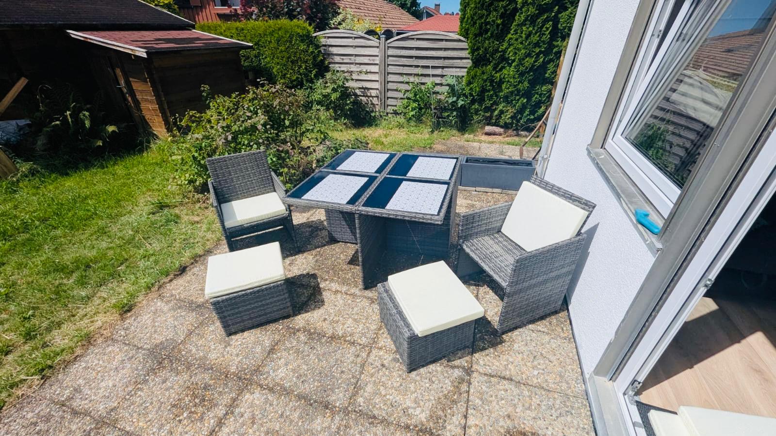 kleine Terasse mit Glastisch und 4 Stühlen vor einer Ferienwohnung