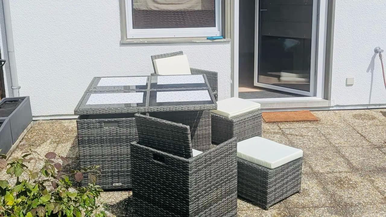 kleine Terasse mit Glastisch und 4 Stühlen vor einer Ferienwohnung