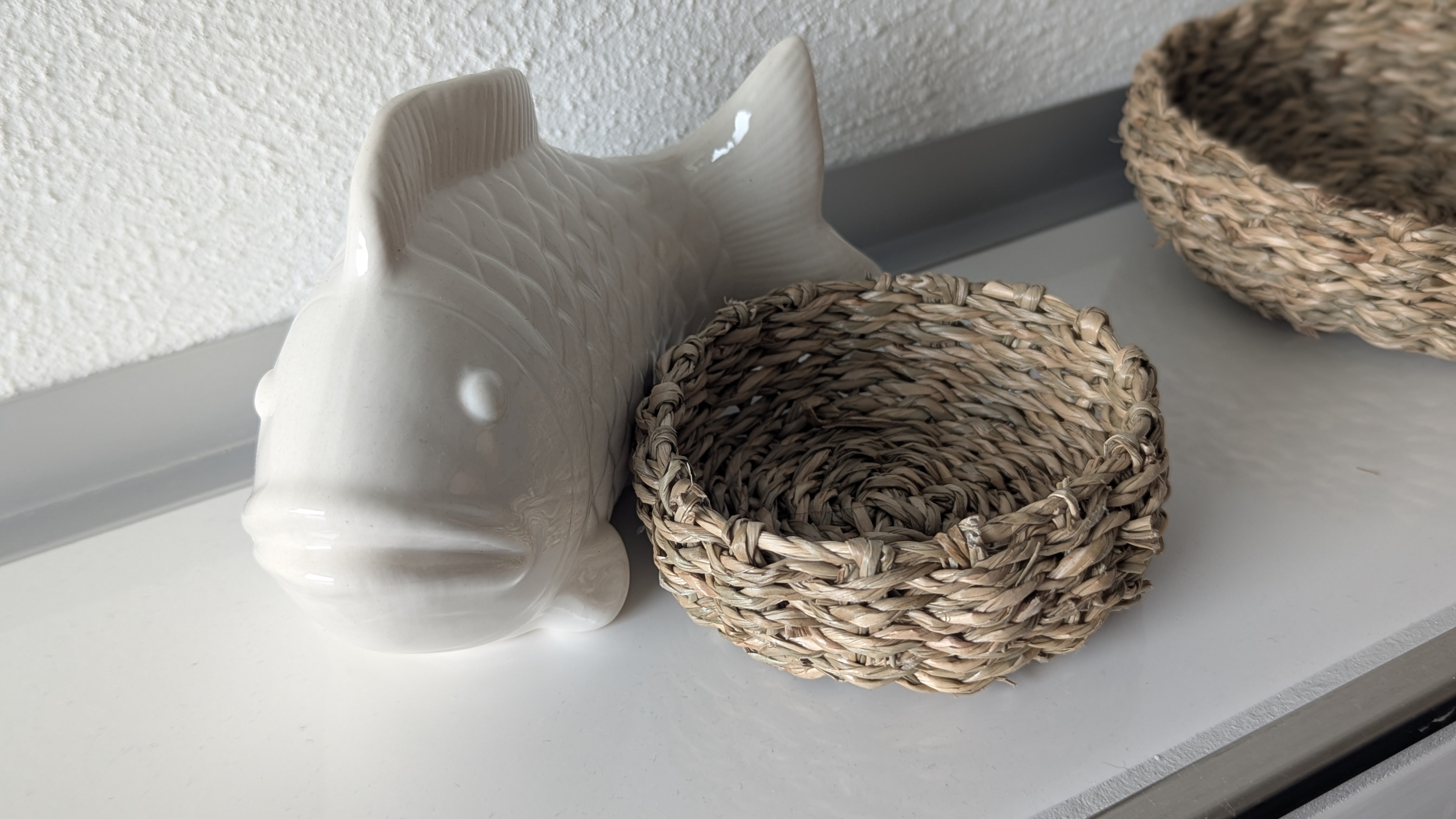 Dekoration mit Porzellanfisch und Bastkörbchen